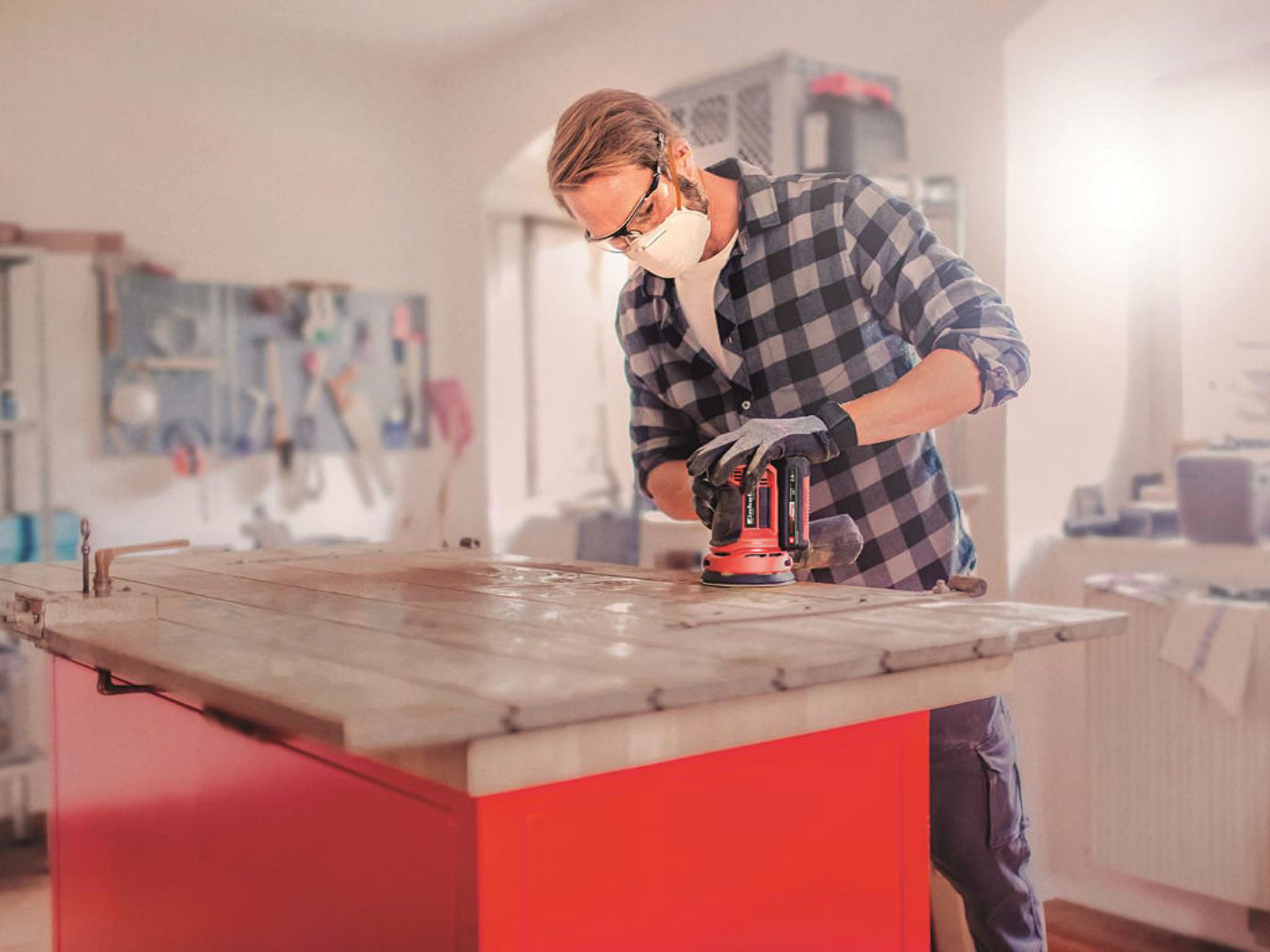 A man is sanding a door with a rotating sander