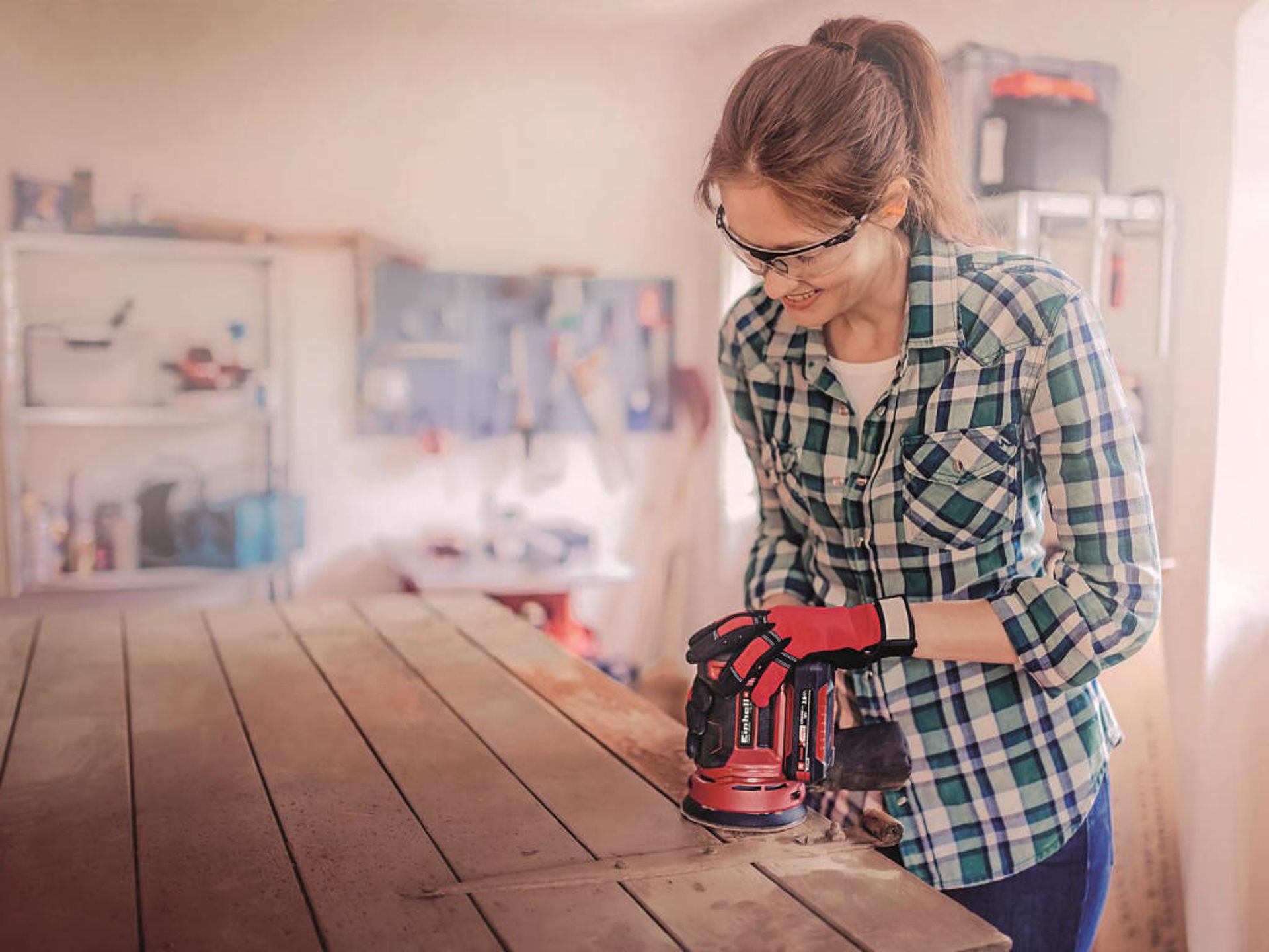 A woman is sanding a door with a rotating sander